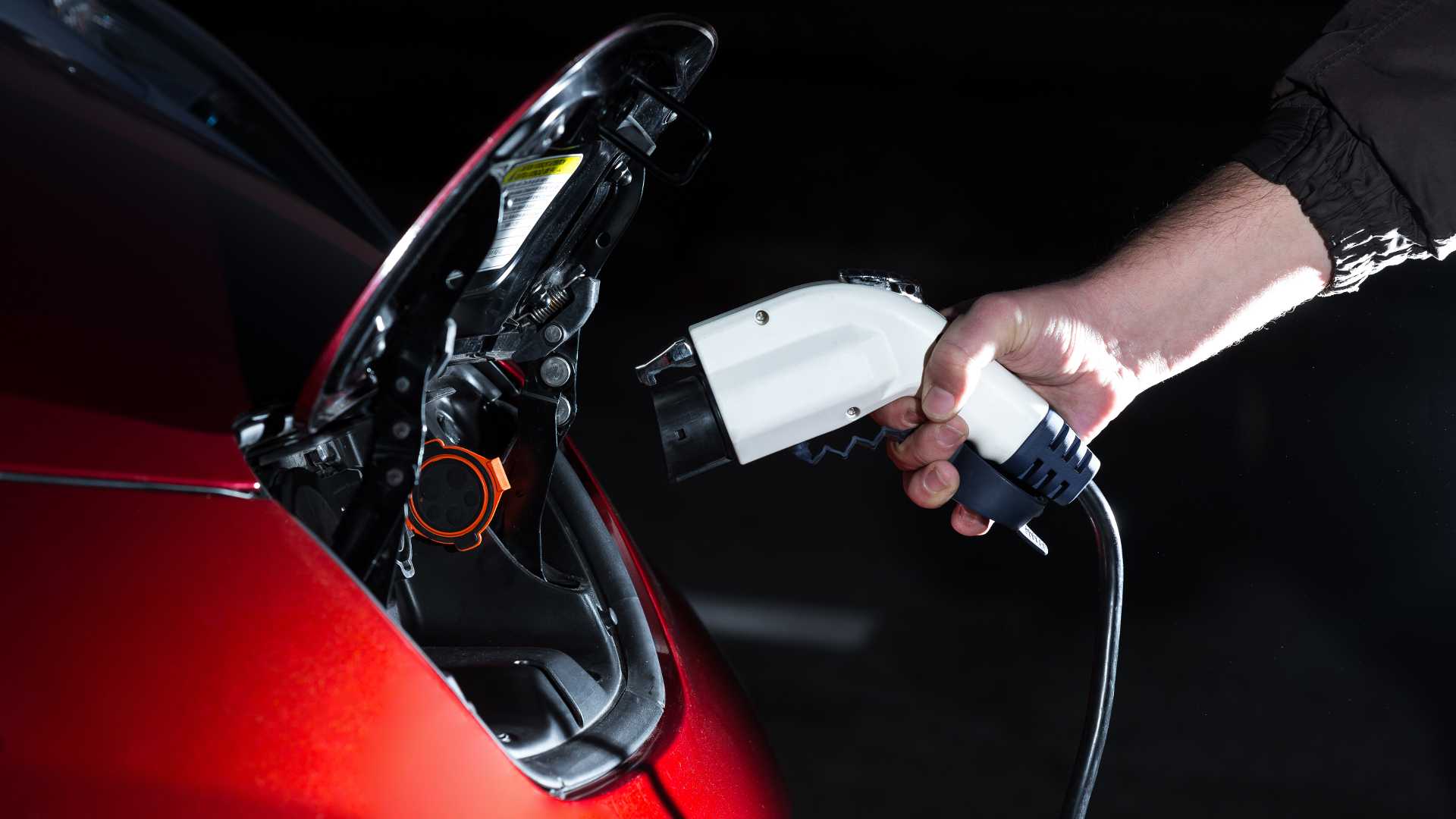 Man plugging in electric car in the evening